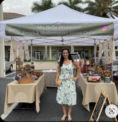 a woman standing in front of a table with food on it and an umbrella over her