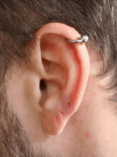 a close up of a man's ear with a piercing in the middle of it