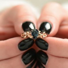 a woman's hand holding a black and gold ring