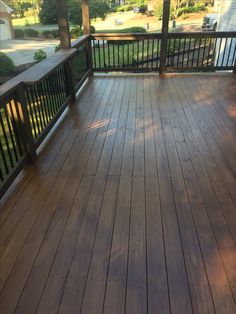 a wooden deck with railings and trees in the background