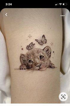 a small tiger cub with butterflies on its head and behind it is a butterfly tattoo