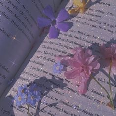 an open book with pink and purple flowers on it's page, next to the pages are glittered stars