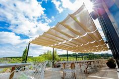 the sun shines brightly on an outdoor patio with white chairs and tables set up