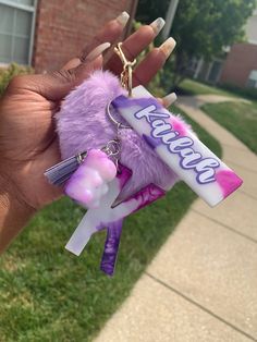 a person holding a candy bar keychain in front of a brick building with grass