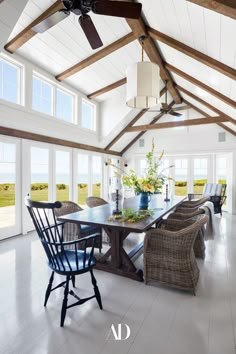 a dining room table with wicker chairs in front of large windows overlooking the ocean