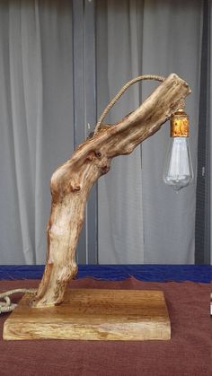 a wooden table lamp with a light bulb on it's end and a piece of wood sticking out of the base