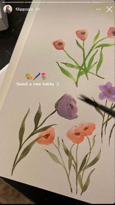 someone is painting flowers with watercolors on the paper and using scissors to draw them