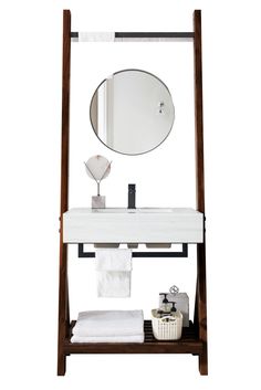 a white sink sitting under a mirror next to a wooden stand with towels on it