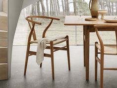 a wooden table with two chairs and a vase sitting on top of it next to a window