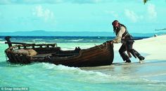 a man in pirate garb pulling a boat out of the water on a beach