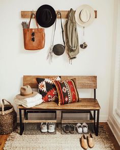 a wooden bench with hats and other items hanging on it's wall next to shoes