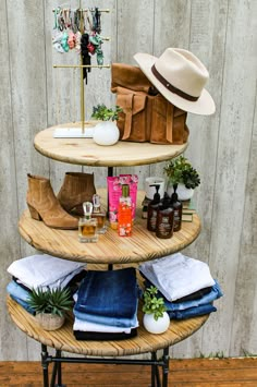 a three tiered shelf with hats, clothing and other items on it in front of a wooden wall