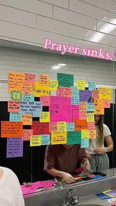 a man and woman standing in front of a counter covered with sticky notes