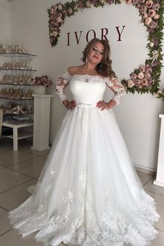 a woman wearing a white wedding dress with long sleeves and an off the shoulder top