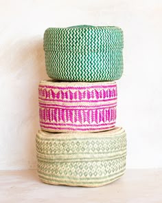 three baskets stacked on top of each other in different colors and patterns, one has a green lid