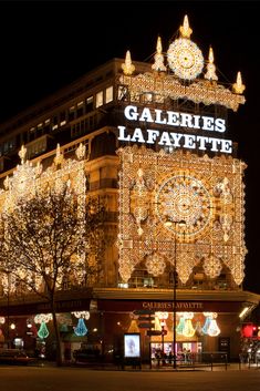 a large building with christmas lights on it's sides and the words galeries lafayette lit up at night