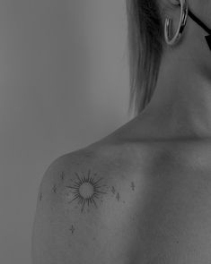 the back of a woman's shoulder with sun and stars tattoo on her left side