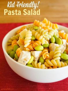 a white bowl filled with pasta salad on top of a red table