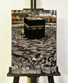 an easel with a painting of the ka'bah on it in front of a white wall