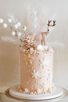 a pink cake decorated with white snowflakes and reindeer figurines on top