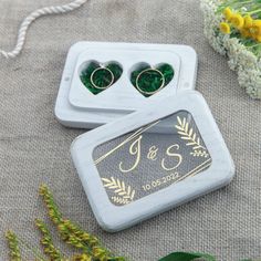 two green heart shaped earrings sitting on top of a white box next to yellow flowers