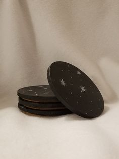 four black coasters with stars on them sitting on a white cloth covered tablecloth