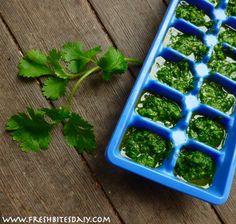 an ice tray filled with green vegetables on top of a wooden table