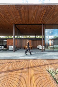 a person walking in front of a building with wooden flooring and large glass windows