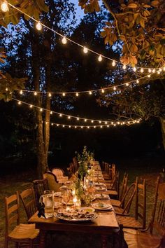 an outdoor dinner table is set with candles and place settings