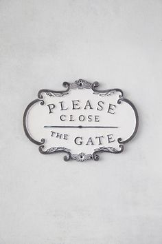 a sign that says please close to the gate on a white wall with black lettering