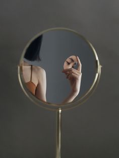 a woman's reflection in a mirror with her hand on top of the mirror