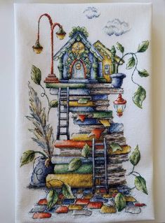 a cross stitched picture of a house on top of a stack of books with a ladder