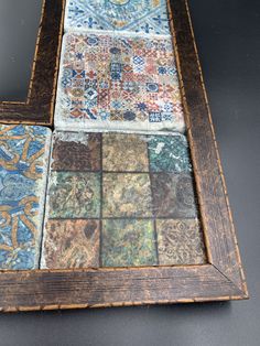 an old wooden frame with several different colored tiles on the bottom and sides, sitting on top of a table