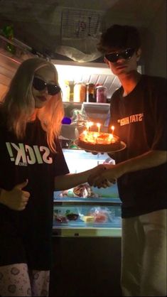 two people standing in front of an open refrigerator holding a plate with food on it