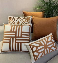 four decorative pillows on a couch next to a potted plant