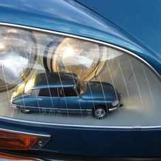 a car is shown in the reflection of it's headlight