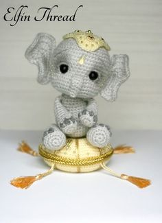 an adorable little crocheted elephant sitting on top of a golden ball with a crown on it's head