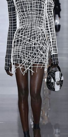 a model walks down the runway in a white dress with black and white lines on it