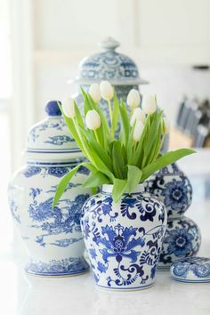 white tulips in blue and white vases on a countertop with plates