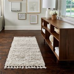 a living room with pictures on the wall and a rug in front of a window