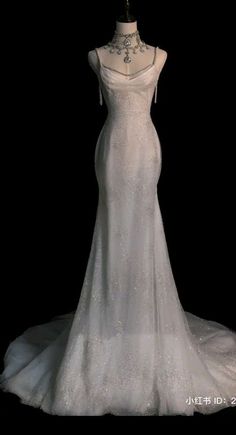 a white wedding dress on display in front of a black background