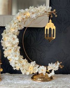 a white wreath with lights on it sitting on top of a table next to a mirror