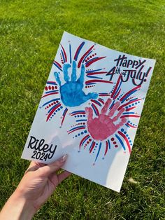 someone is holding up a handprint on the grass with happy 4th july written in red, white and blue