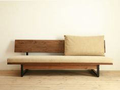 a wooden bench sitting on top of a hard wood floor next to a white wall