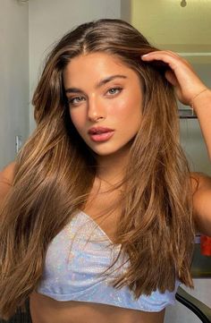 a beautiful young woman with long brown hair wearing a white bra and posing in front of a mirror