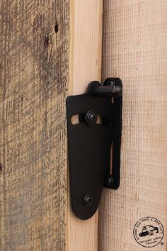 a black door handle is attached to the side of a wooden wall with wood planks