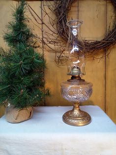 two glass vases sitting on top of a table next to a pine branch wreath