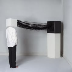 a man standing in front of a black and white sculpture with long hair on it's head