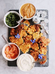 an overhead view of fried food and dipping sauces on a slate platter with silverware