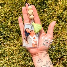 a person's hand holding a keychain with a photo and tassel on it